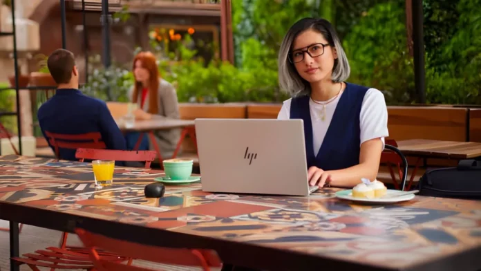 Person using HP EliteBook laptop in an outdoor café environment for work